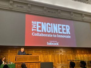 Photo of a projector screen showing the text "The Engineer, Collaborate to Innovate" in large bold text. Underneath the text is says "In association with Babcock"